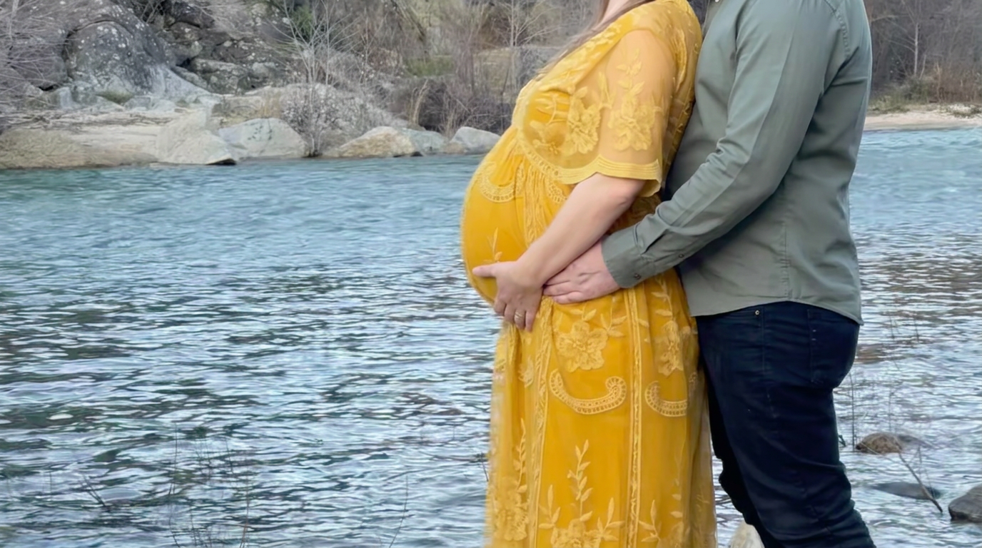 Expecting parents by the river under a covered bridge